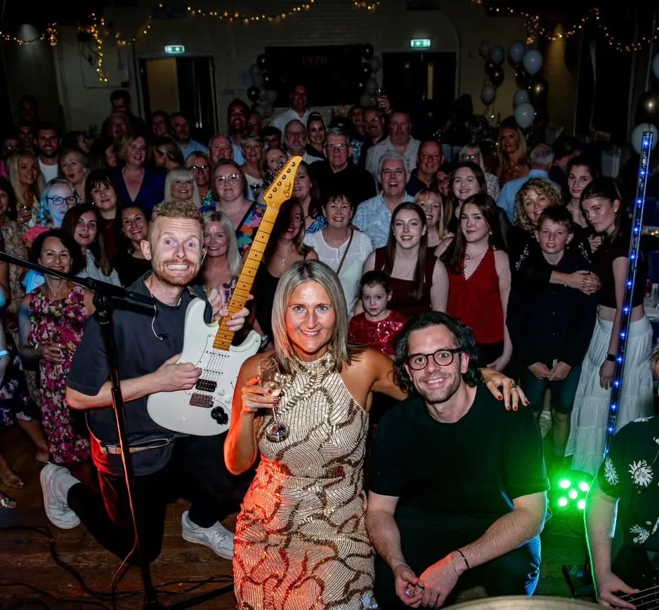Band members posing with happy crowd on the dance floor at a live venue